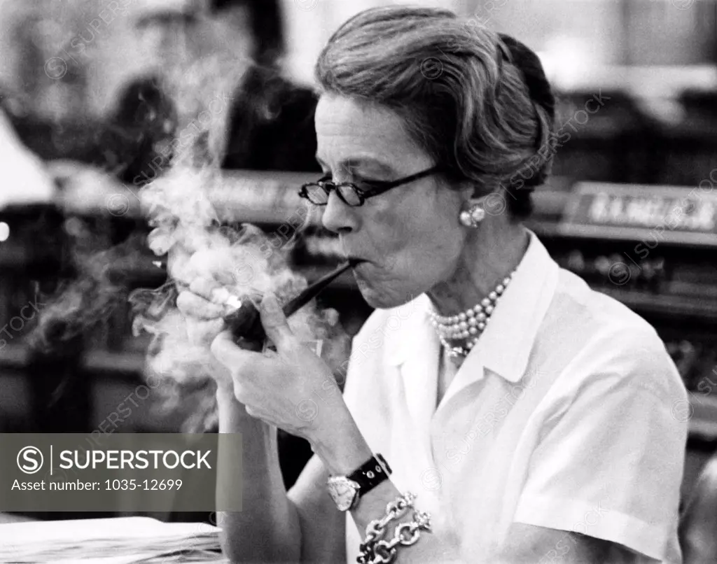Trenton, New Jersey:  April 15, 1970 Legislator Millicent Fernwick lights up her pipe at her desk in the State Assembly. She is pushing for the New Jersey Legislature to give the state's women a new bill of rights.