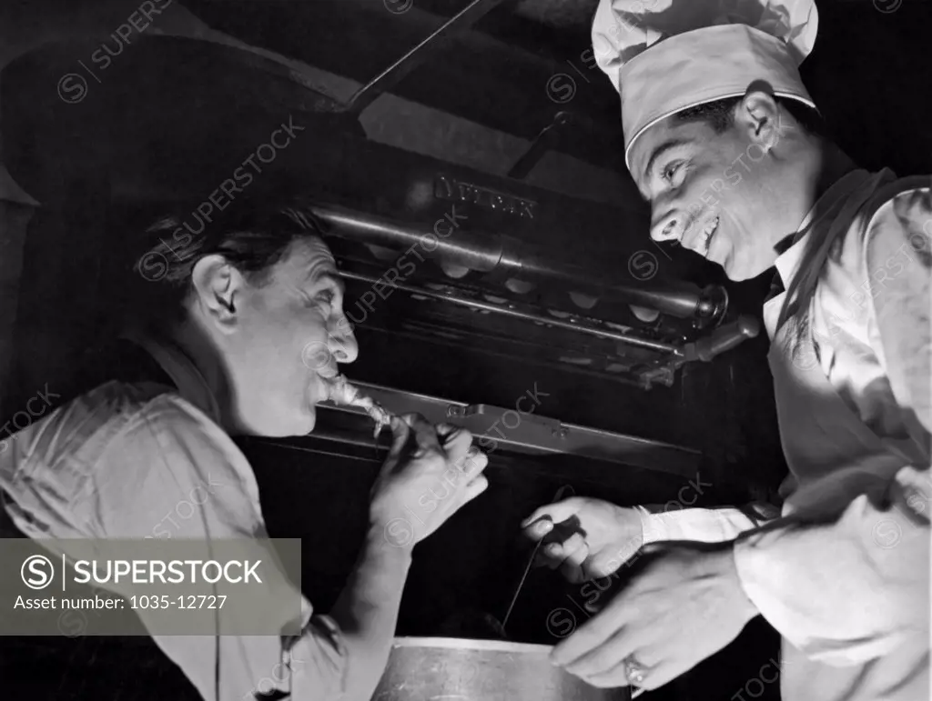 San Francisco, California:  December 14, 1937. Opera tenor Tito Schipa tries out chef Joe DiMaggio's favorite spaghetti sauce when he dropped into the Yankee slugger's restaurant in San Francisco.