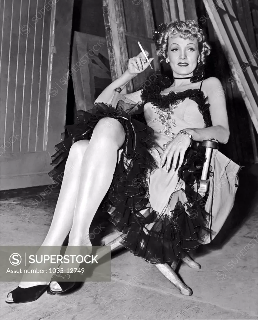 Hollywood, California:  1939. Actress Marlene Dietrich takes a cigarette break during the filming of 'Destry Rides Again'.