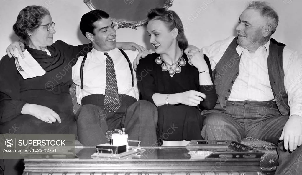 San Francisco, California:  c. 1940 Joe Dimaggio sits on a couch with his wife, actress Dorothy Arnold, and his parents, Giuseppe and Rosalie DiMaggio.