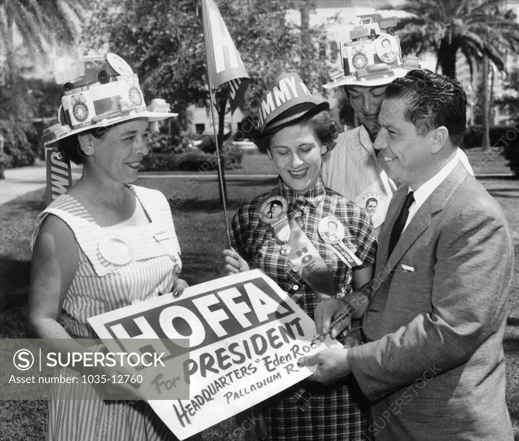 Miami Beach, Florida:  October 1, 1957 Teamsters union vice president JImmy Hoffa autographs a placard for him for a group of women campaigning for his run for president of the Teamsters.