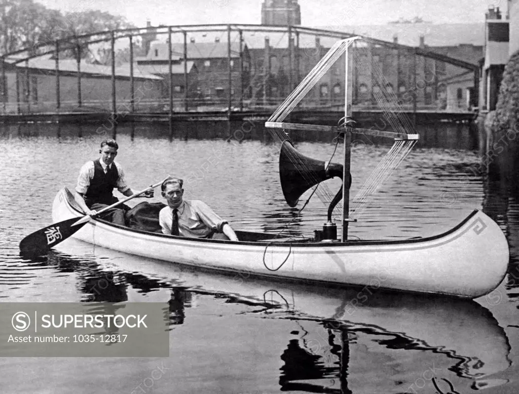 New York, New York:  July 22, 1922 These ingenious radio fans have rigged their canoe with an amplifier and aerial to hear music on the water. They can now have music wherever they are and have no such trouble as winding up a phonograph.