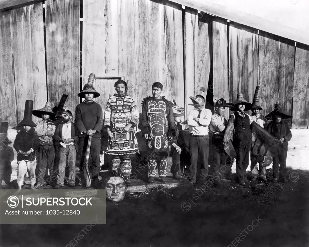Chilkat, Alaska: 1895 Native Americans in old dancing costumes in front of Chief Klart-Reech's house.