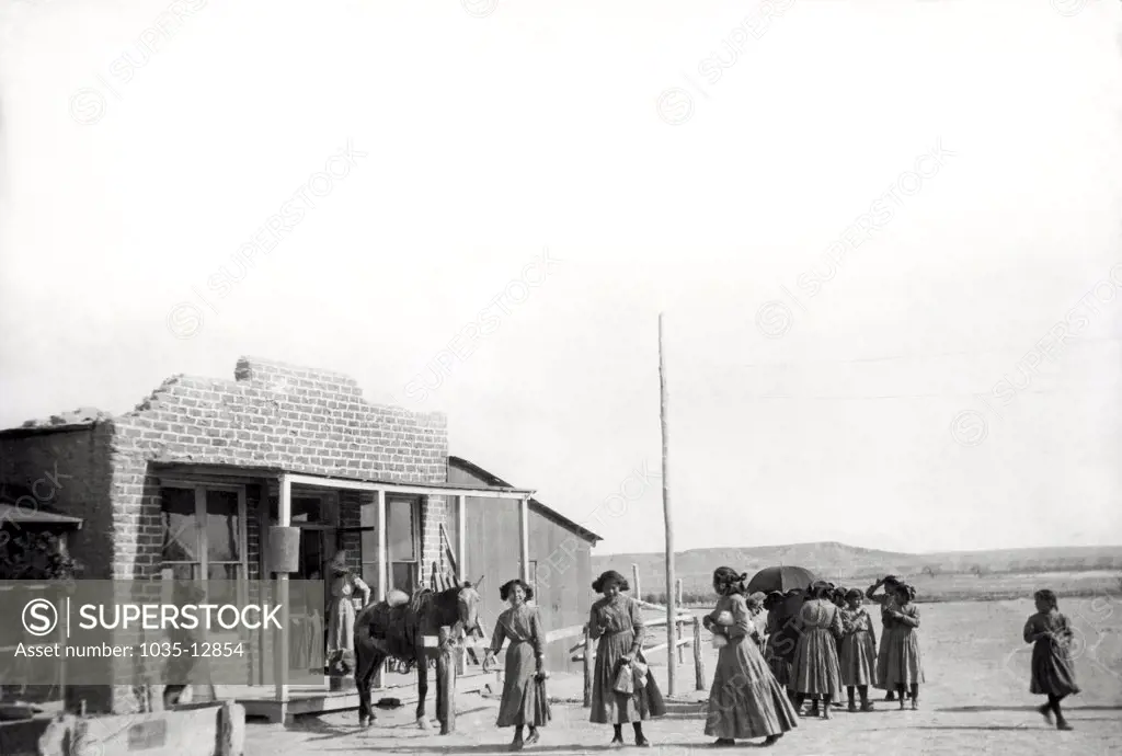 Shiprock, New Mexico:  c. 1912 The Navajos are threatening to revolt aginst U.S. rule, but here the Navajo Indian girls are going shopping on a Saturday afternoon at the local trading store on the reservation.