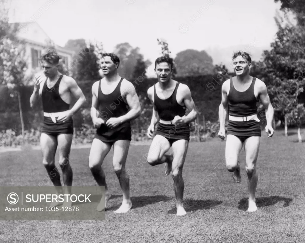 Los Angeles, California: c. 1927 Jack Dempsey works out in his yard with, L-R, sprinter Frank Wykoff, Dempsey, sprinter Frank Lombardi, and Olympic giold medal discus champion, Bud Houser. Dempsey is planning a rematch with Gene Tunney.