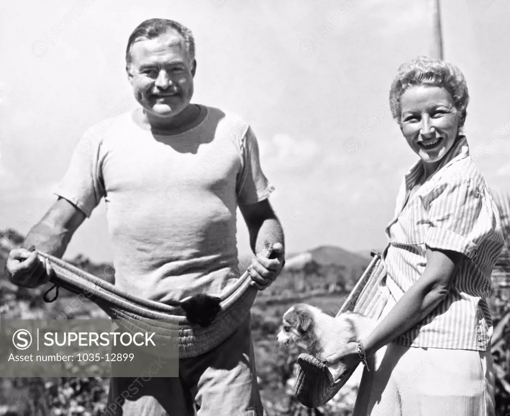 Havana, Cuba: March 20, 1946 Author Ernest Hemingway and his fourth wife, Mary Welsh, hold their pets in jai alai baskets on the Hemingway farm in San Francisco de Paulo, a Havana suburb.