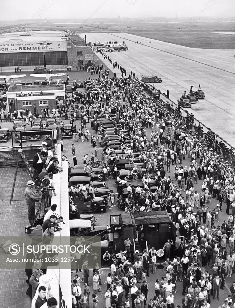 New York, New York:  July 14, 1938 Part of the huge crowd on hand at Floyd Bennett Airport in Brooklyn when Howard Hughes landed his Lockheed 14N Super Electra airplane after leaving there and flying around the world in a new record of 3 days, 19 hours and 14 minutes, breaking Wiley Posts's record.