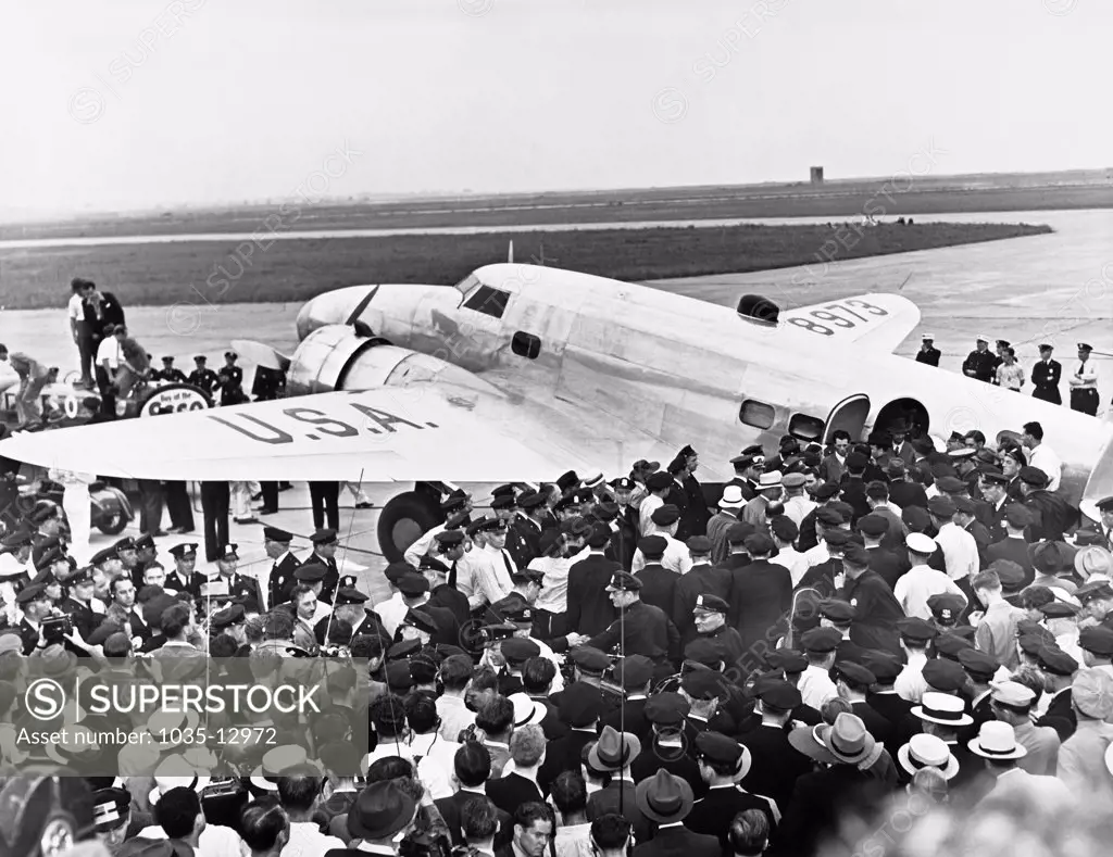New York, New York:  July 14, 1938 Police surround Howard Hughes' Lockheed 14N Super Electra airplane at Floyd Bennett Airport in Brooklyn when he landed there after flying around the world setting a new record of 3 days, 19 hours and 14 minutes, breaking Wiley Posts's record. It was part of a promotion to attract people to the New York World's Fair.