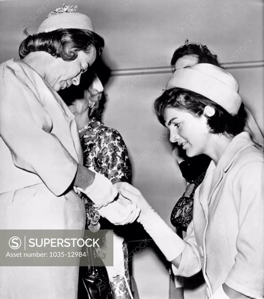 Washington, D.C.:  May 18, 1961 Mrs. Jacqueline Kennedy inspects a gold bracelet worn by Mrs.Barry Goldwater at a luncheon given for Mrs. Kennedy by wives of the members of Congress.