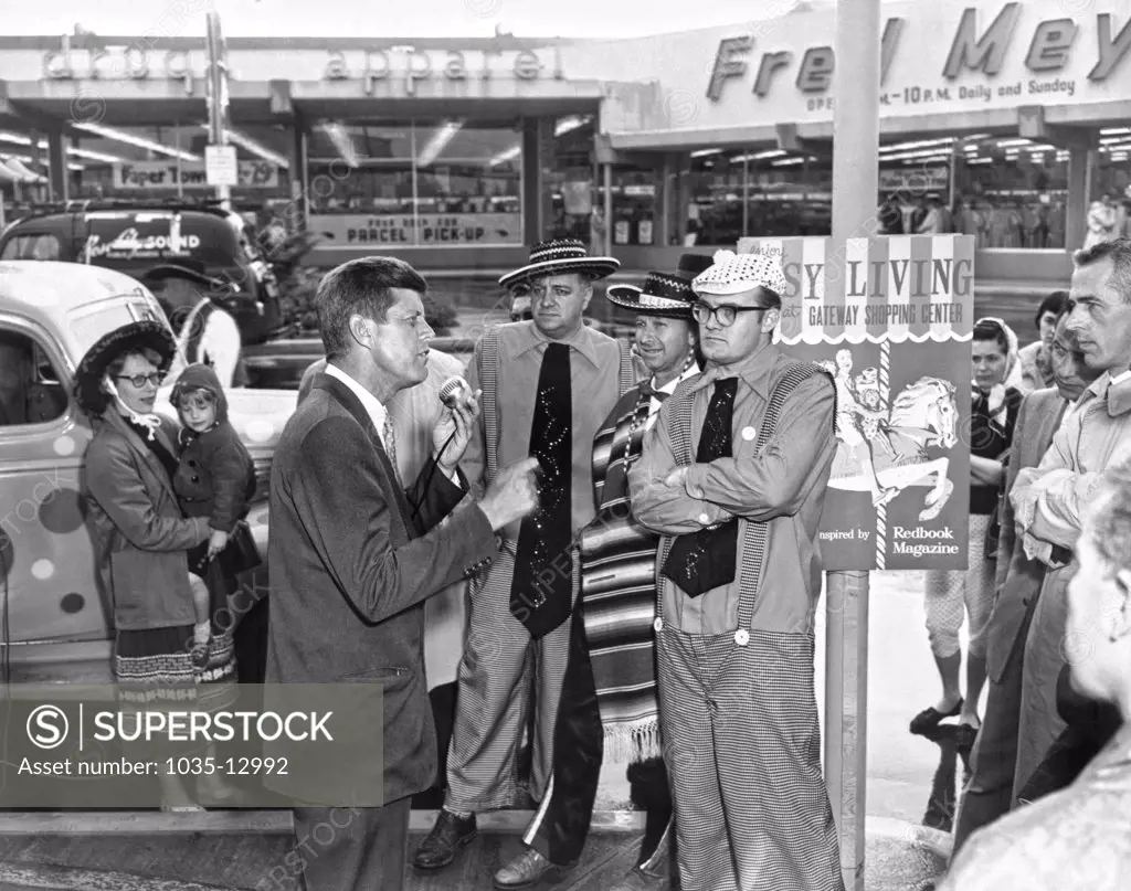 Portland, Oregon:  May 25, 1960 Senator John Kennedy of Massachusetts campaigns at the Gateway shopping center two days before the Oregon primary. Members of the Fun-O-Rama Funmakers listen attentively.