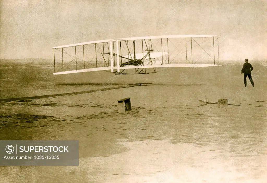Kitty Hawk, North Carolina:  December 17, 1903 An intaglio-gravure of Orville Wright flying during the first powered and sustained flight while Wilbur is on the ground at right.