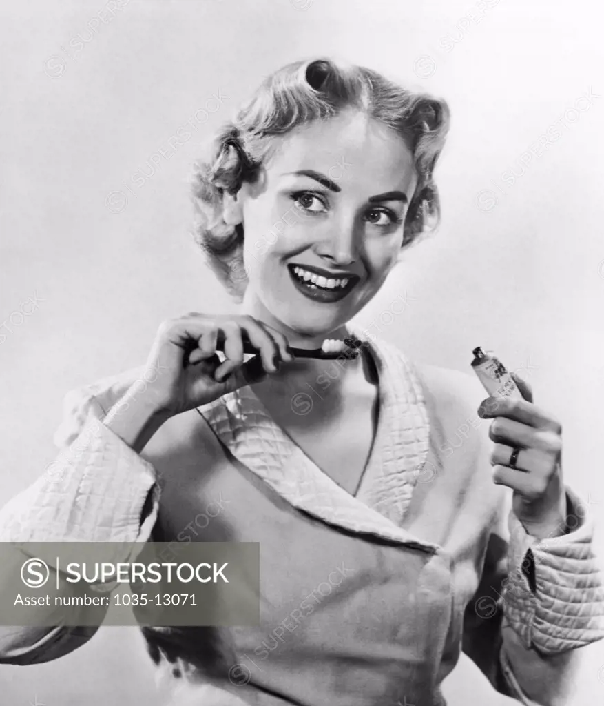 United States:  May, 1952 An attractive young woman prepares to brush her teeth.
