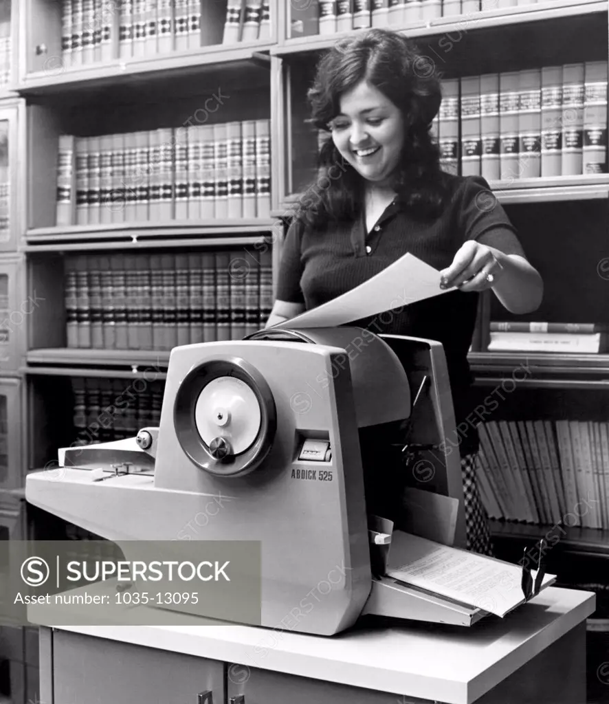 United States:  c. 1967 A woman using an A.B. Dick 525 mimeograph machine.