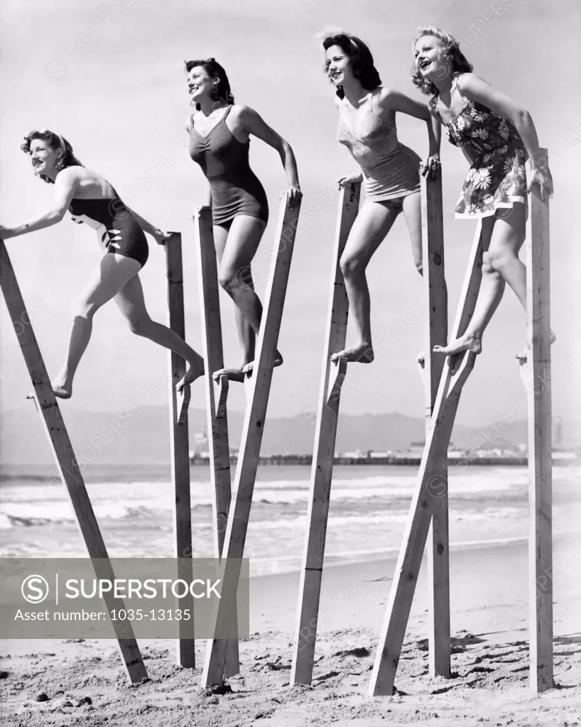 Venice, California:  March 3, 1942 Four young women try their stilt walking skills on the beach in Los Angeles.