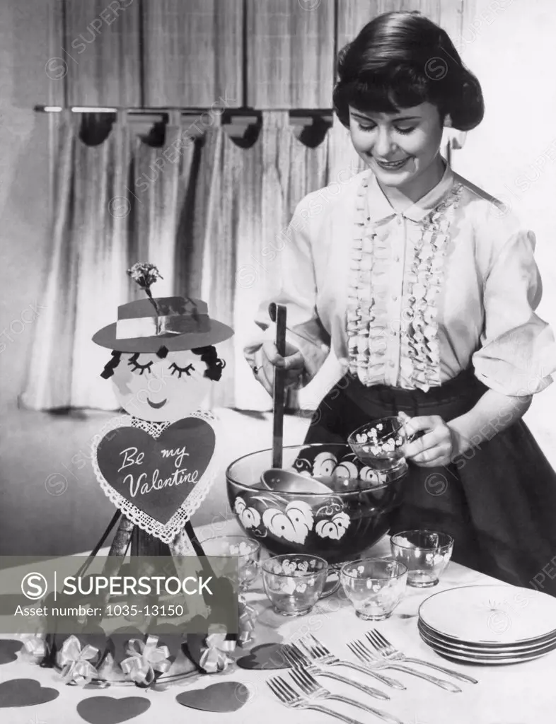 United States:  February 14, 1957 A young woman teenager serves punch at a Valentine's Day party.