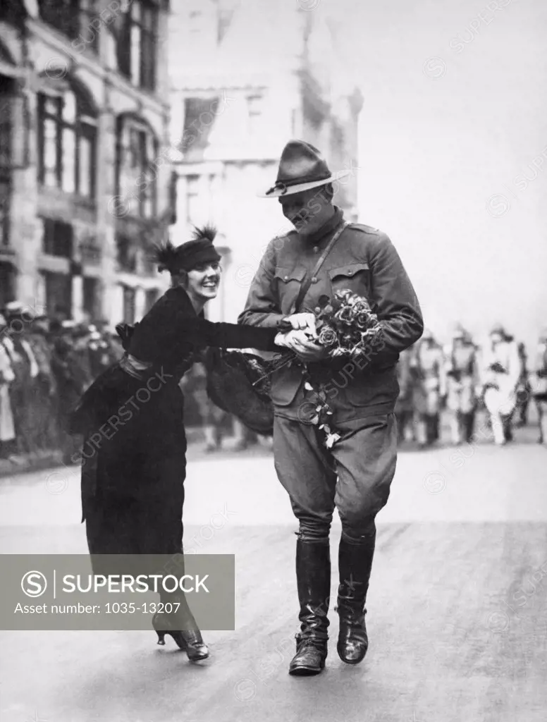 New York, New York:  August 7, 1919 A young woman giving a bouquet of flowers to a returning WWI soldier in the Welcome Home parade
