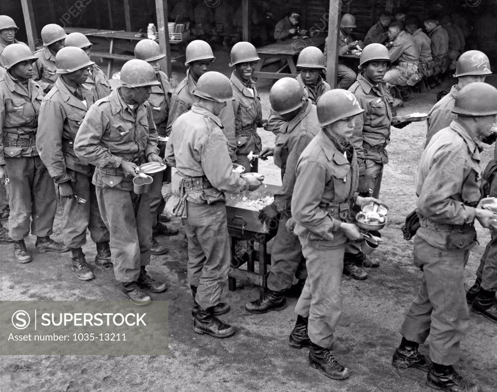 United States: c. 1940. African American and white troops in a chow line at basic training.