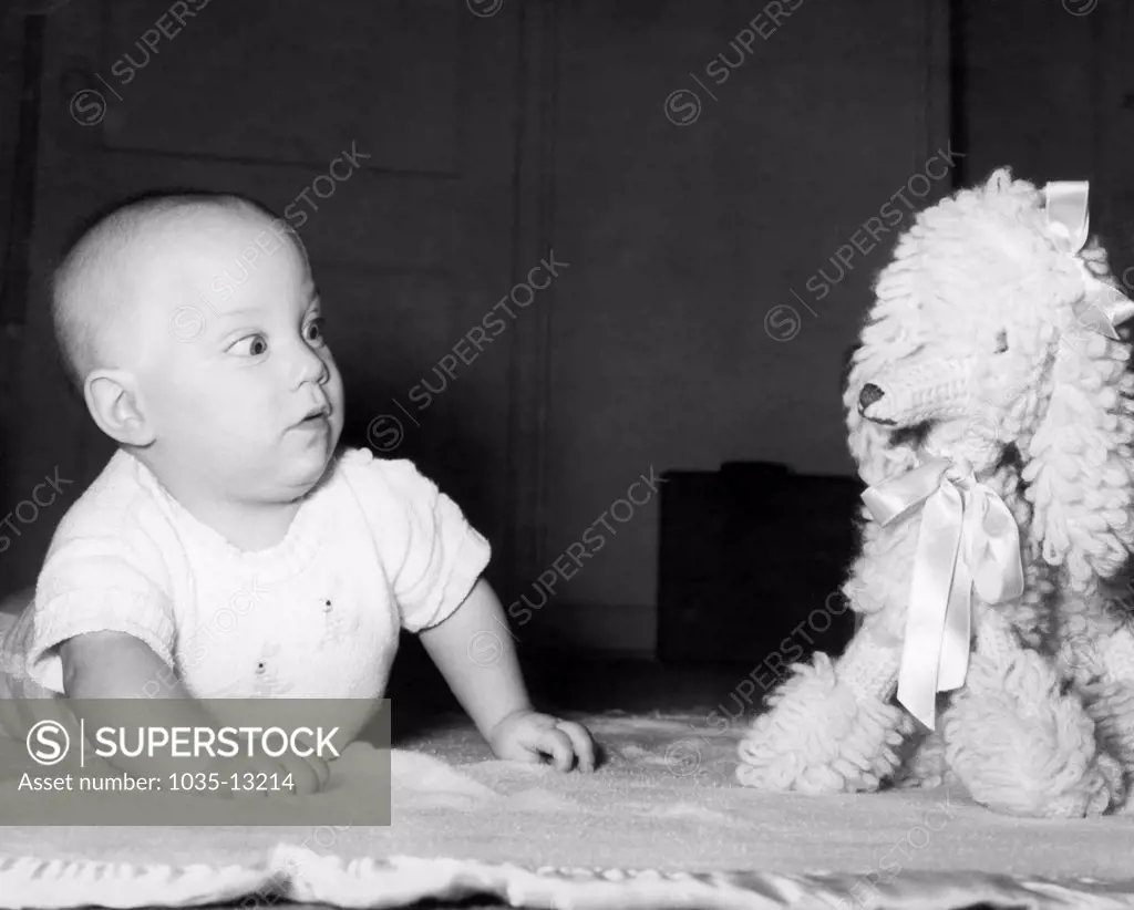 Chicago, Illinois:  c. 1956 A baby appears to be surprised by a stuffed animal toy.
