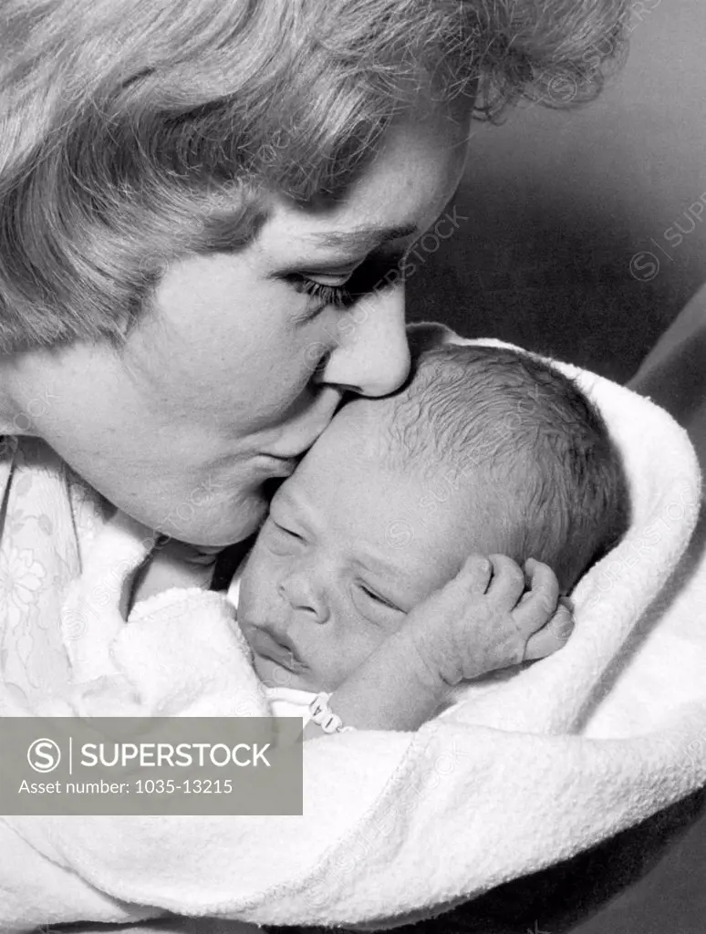 United States:  c. 1958 A mother gives her new born baby a kiss.