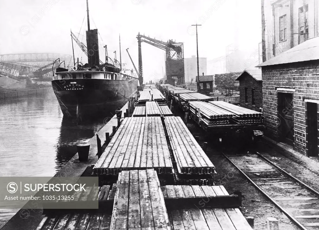 New York, New York:   c. 1912 The SS Neptune next to railroad flatbed cars loaded with rairoad tracks on the docks.