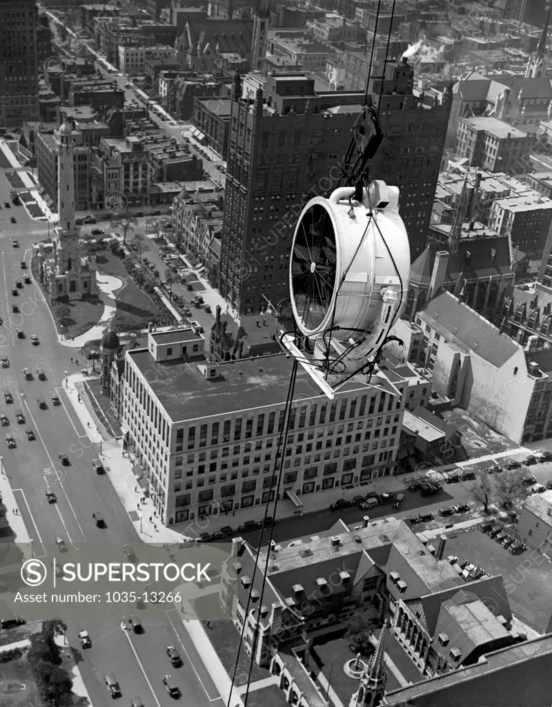 Chicago, Illinois:  August 12, 1930 The Lindbergh lamp being hoisted to the top of the Palmolive building where it will soon be dedicated as the largest beacon in the world. It is the most powerful light of its kind with 2 billion candle power. The next closest is  the one at the Army base in Panama which only has 1 billion candle power.