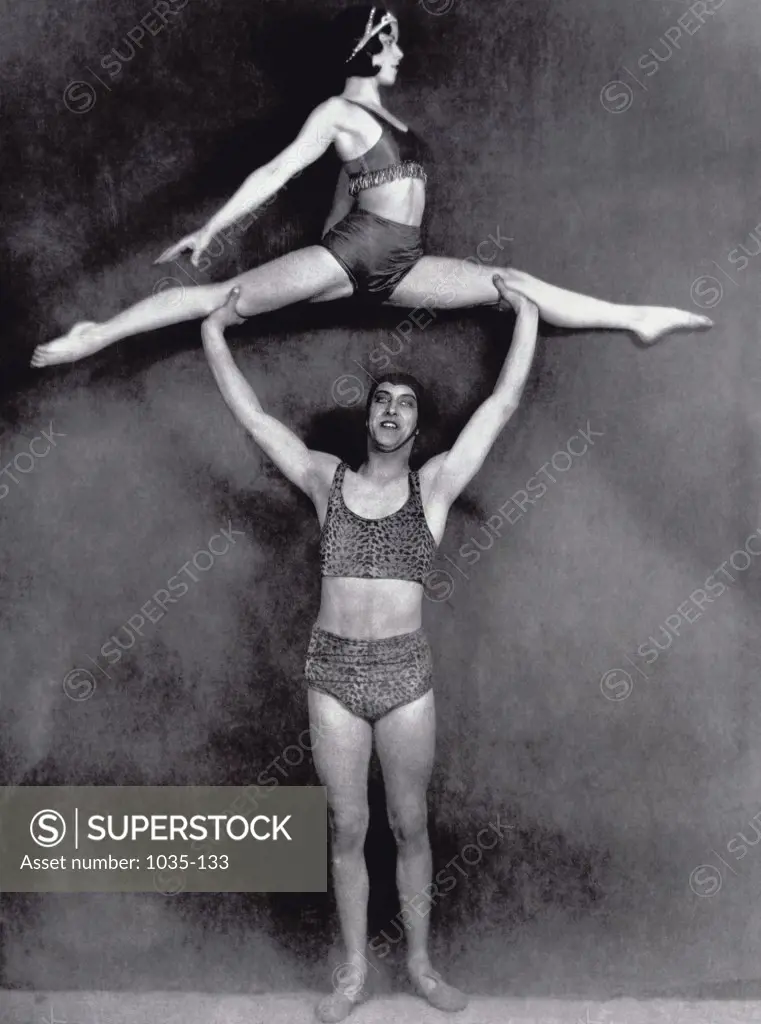 Male acrobat holding a female acrobat over his head
