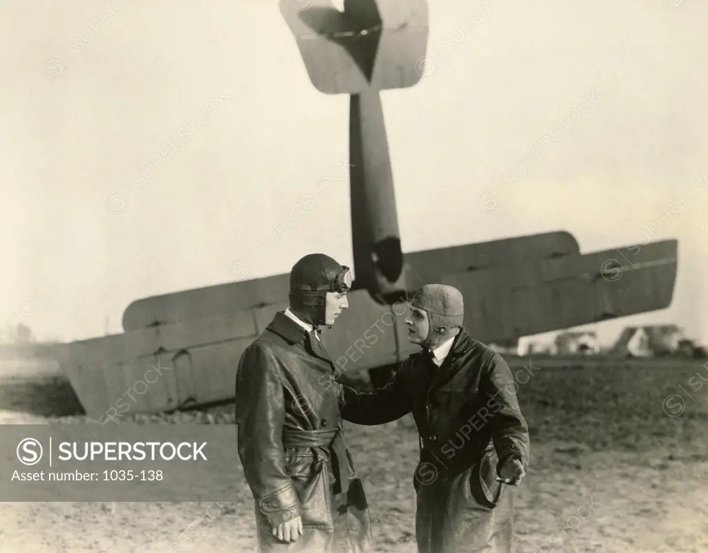 Two pilots standing in front of crashed plane
