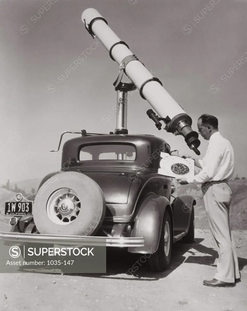 Side profile of a mature man operating astronomy telescope, 1933