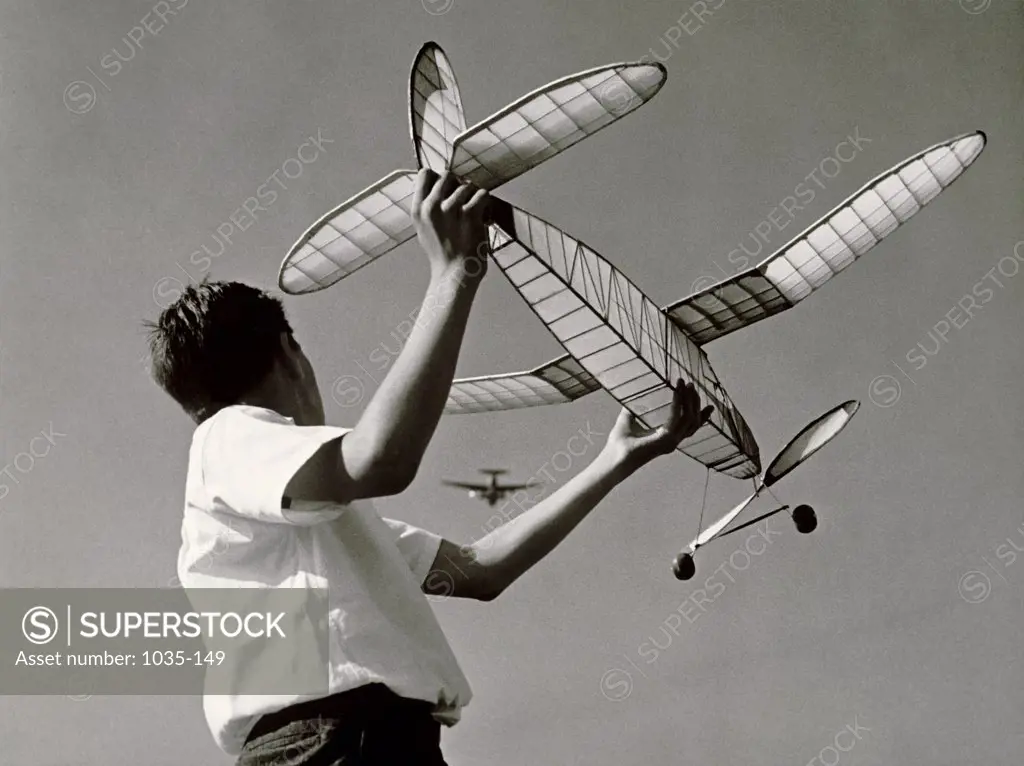 Low angle view of a boy holding a model airplane