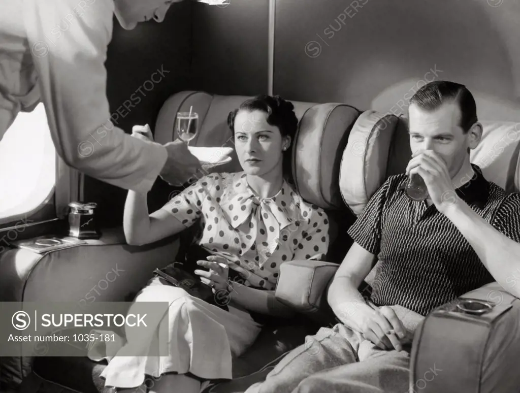 Airplane stewardess serving drinks to passengers in an airplane