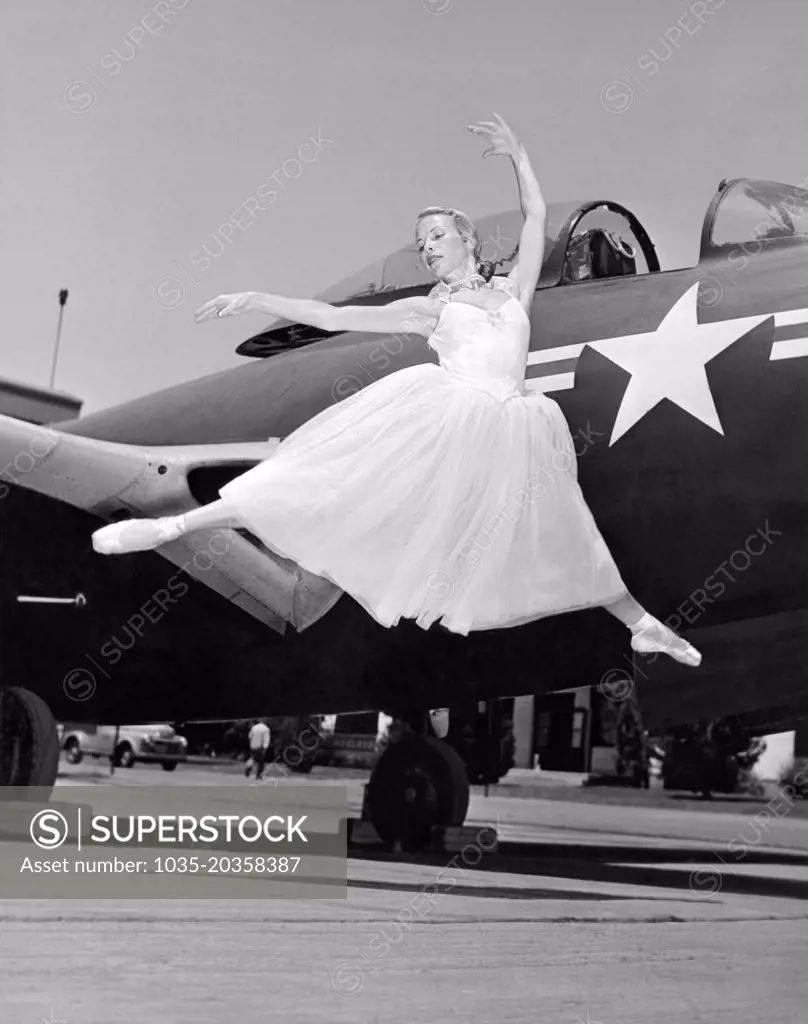 United States:  c. 1946 A ballerina does a graceful leap with an Army Air Corp fighter plane as a backdrop.