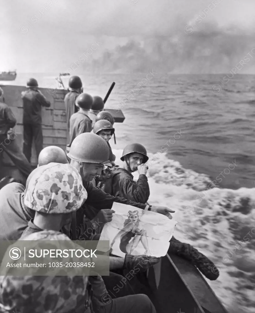 Gilbert Islands, Pacific Ocean:  1943 United States Marines on a landing barge share viewing a pin-up girl as they approach the Japanese held island of Tarawa.