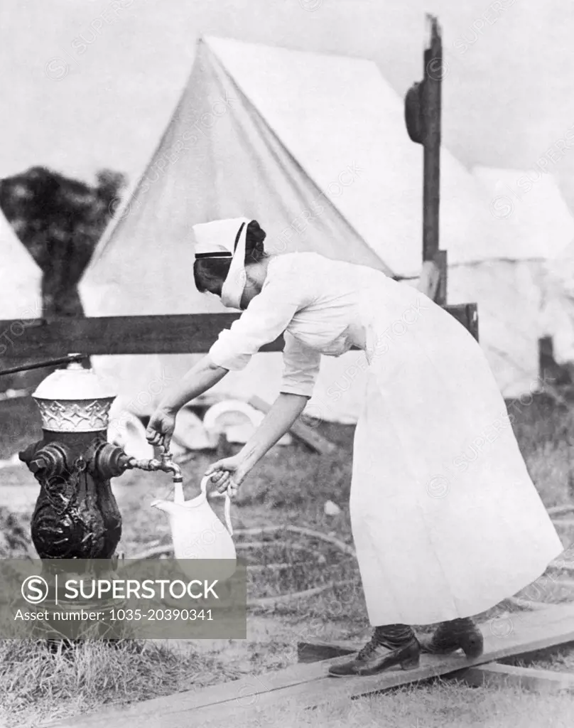 Brookline, Massachusetts:  September 13, 1918 A nurse at the Corey Hill Hospital refills a water pitcher while wearing a protective mask to protect herself from the influenza epidemic. A special camp has been set up there for the Army and Navy members stricken by the flu outbreak.