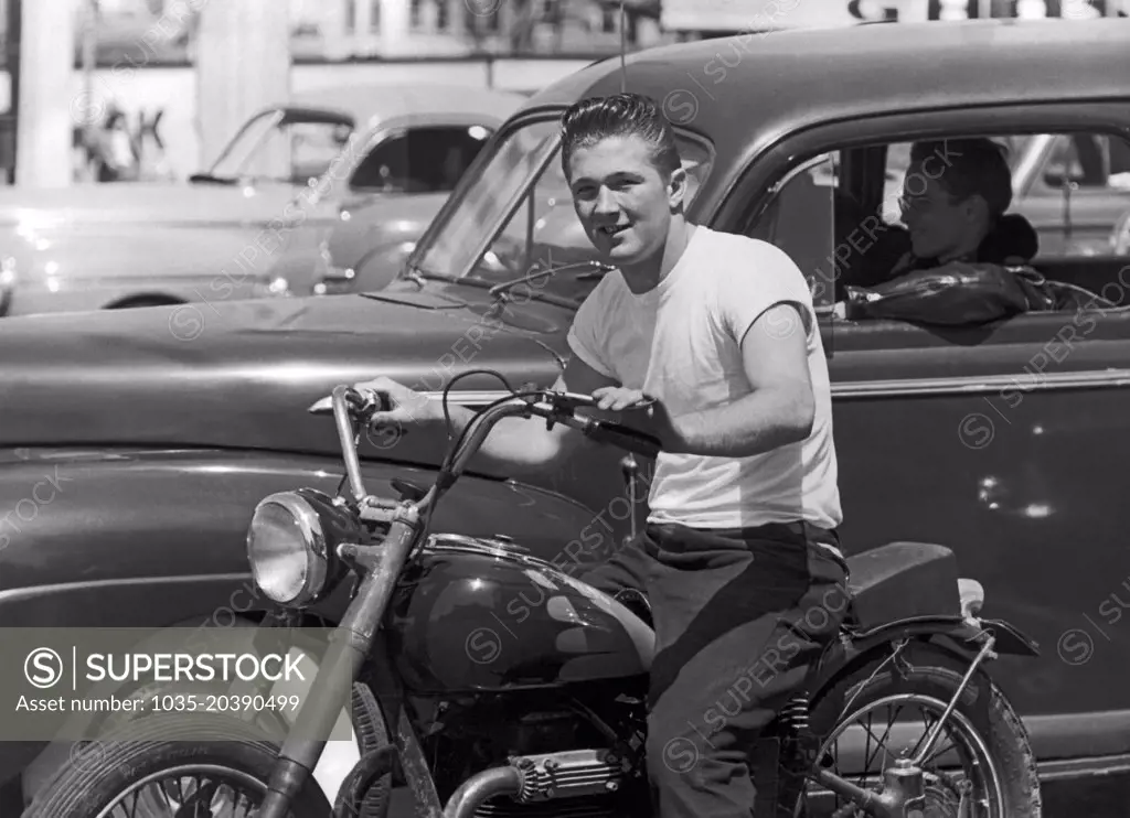 San Francisco, California:  c. 1955 A young man on a motorcycle next to his buddy wearing a leather jacket in a car