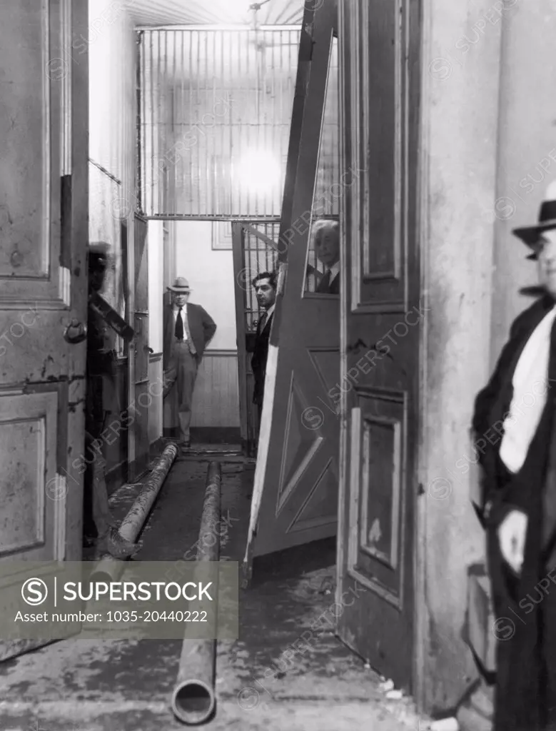 San Jose, California:   November 27, 1933. Police officers look at the 30 foot lengths of pipe that the lynch mob used as battering rams to break down the two iron doors of the jail. The officers' efforts to save the kidnapers, John Holmes and Thomas Thurmond, from the mob were futile.
