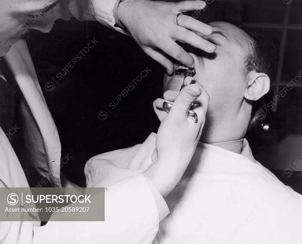 United States:  c. 1933 A patient getting shot of novocain before having a tooth extracted by a dentist.