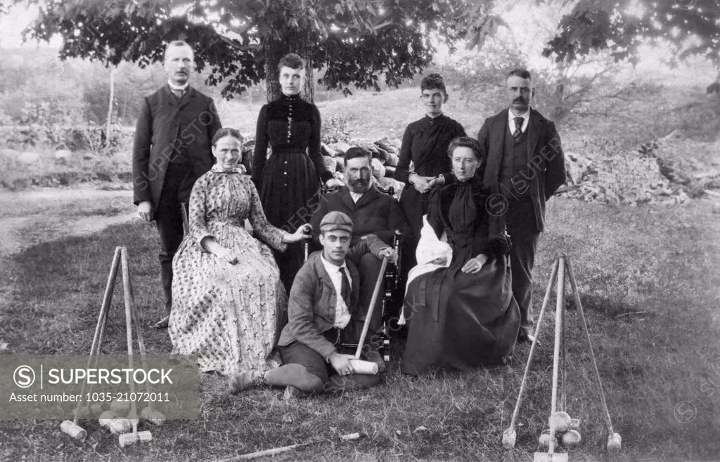 United States:  c. 1890 A family sitting outside for a portrait with their croquet mallets and balls.