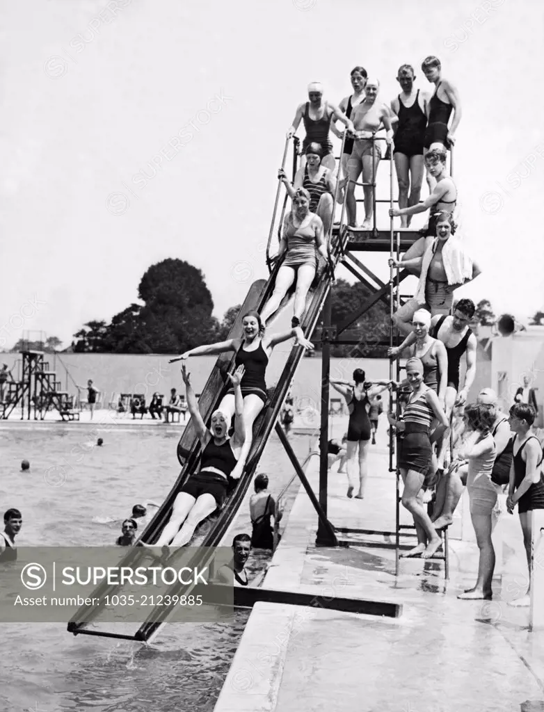 London, England:  June 5, 1933 Swimmers sliding down the water chute at the opening of the new Lagoon Swimming Pool at Orpington Garden Village.