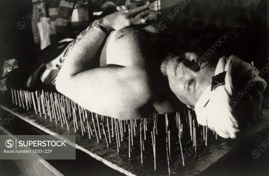 Mid adult man lying on a bed of nails