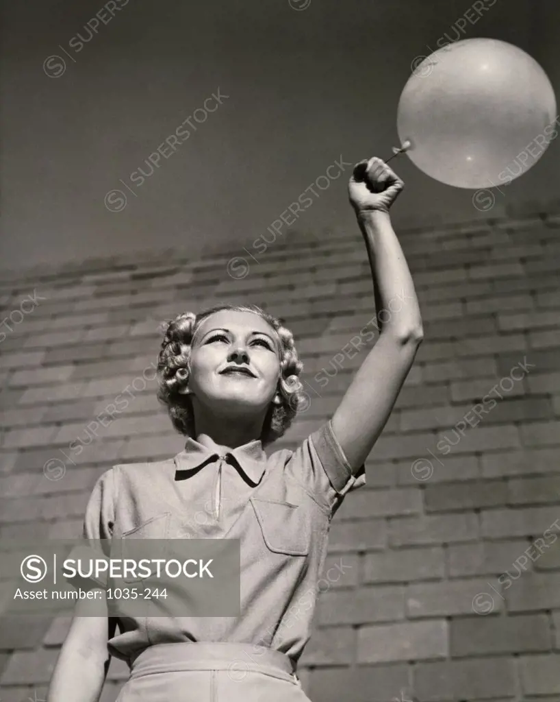 Low angle view of a young woman holding a balloon