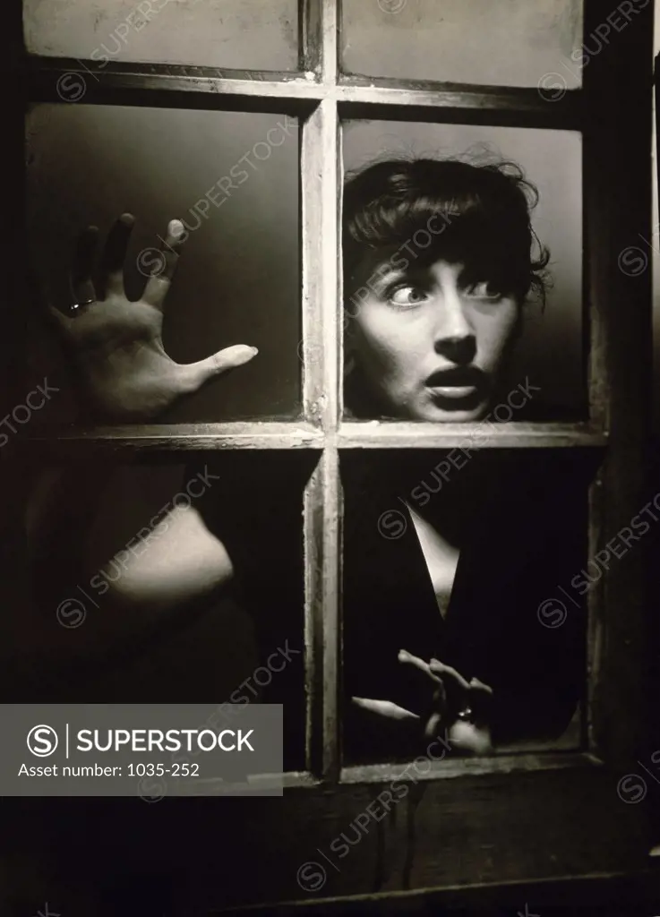 Young woman peering through a window