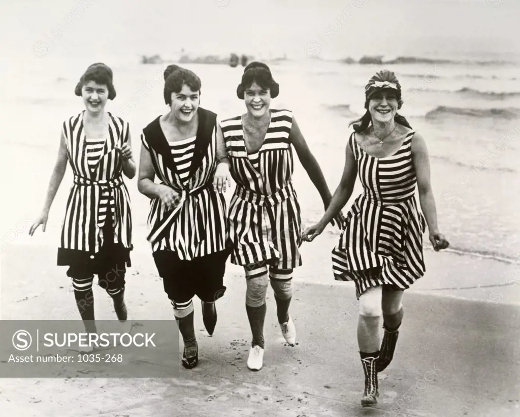 Portrait of four young women running on the beach