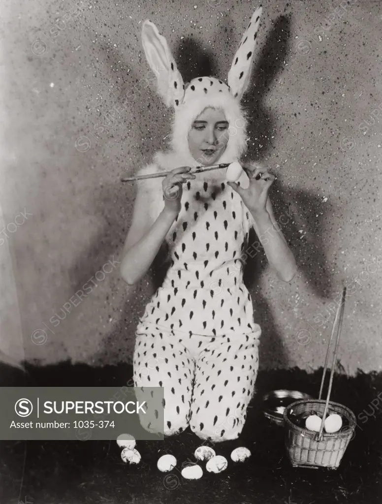 Young woman wearing a rabbit costume coloring eggs