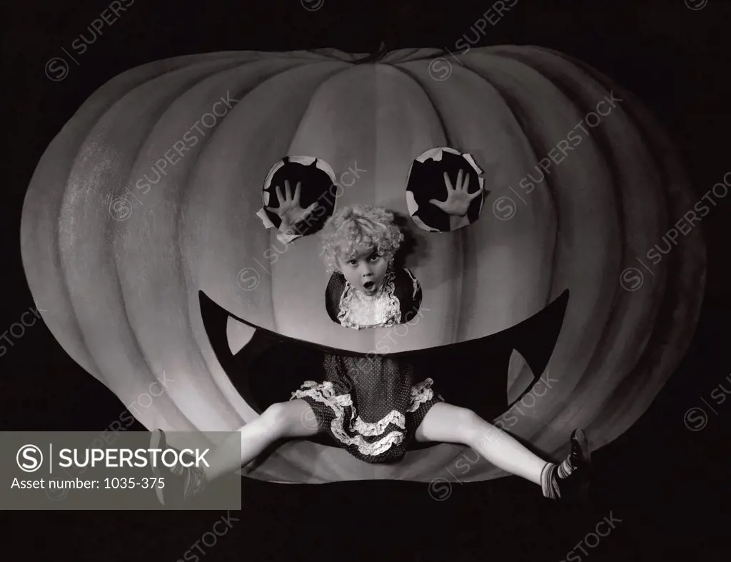 Portrait of a girl sitting in a cut out of a carved pumpkin