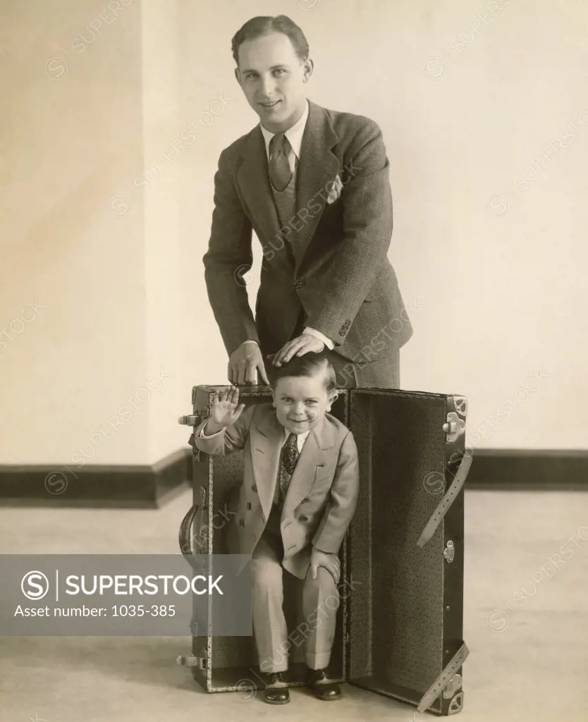 Portrait of a mid adult man putting the smallest man in a suitcase