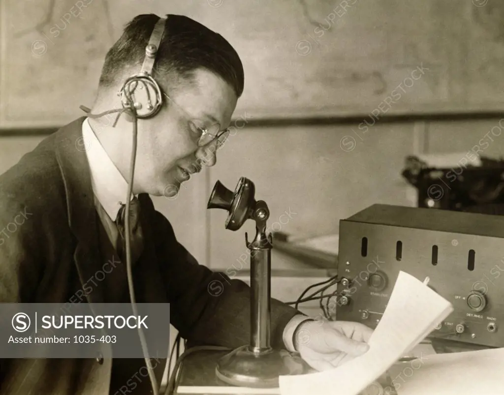 Side profile of a mature man reading a report in front of a microphone, 1922