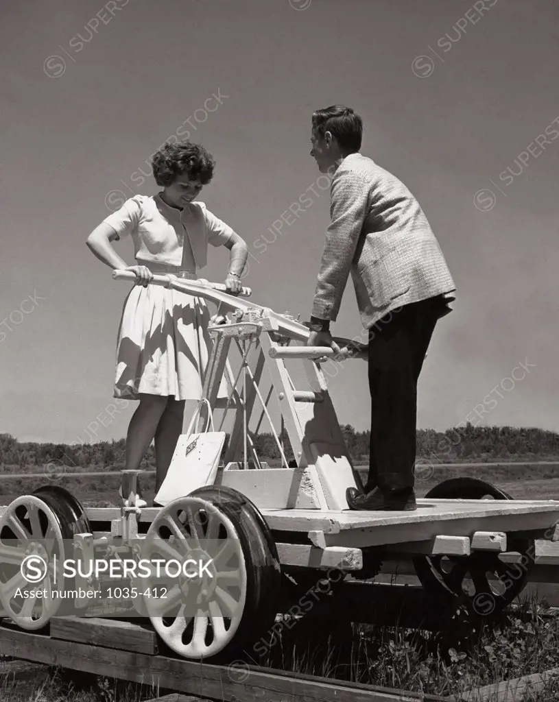 Teenage girl and a teenage boy on a tandem rail trolley