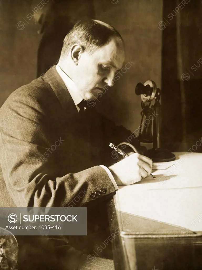 Side profile of a businessman sitting and writing on a desk