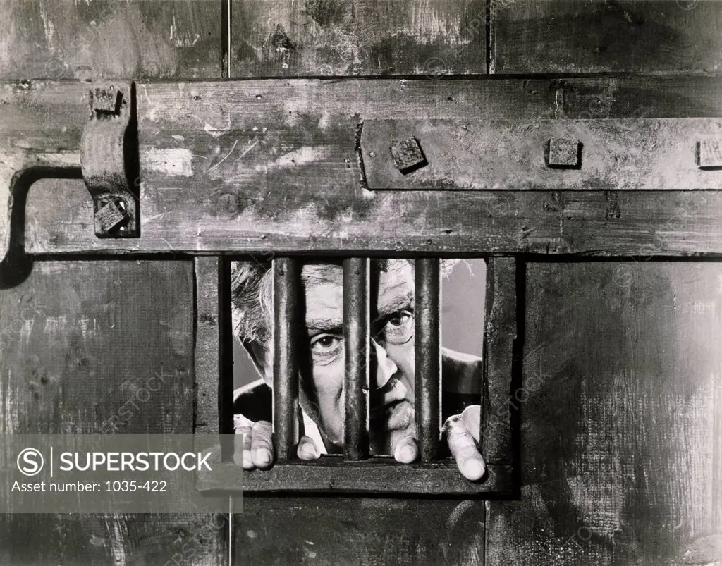 Close-up of a mature man looking through a window of a prison