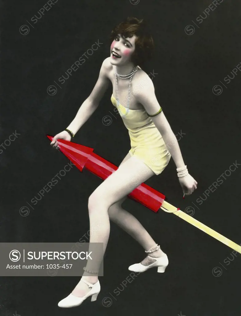Portrait of a young woman sitting on a rocket and lighting it